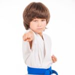 Karate kid. Little boy doing martial arts moves while isolated on white background